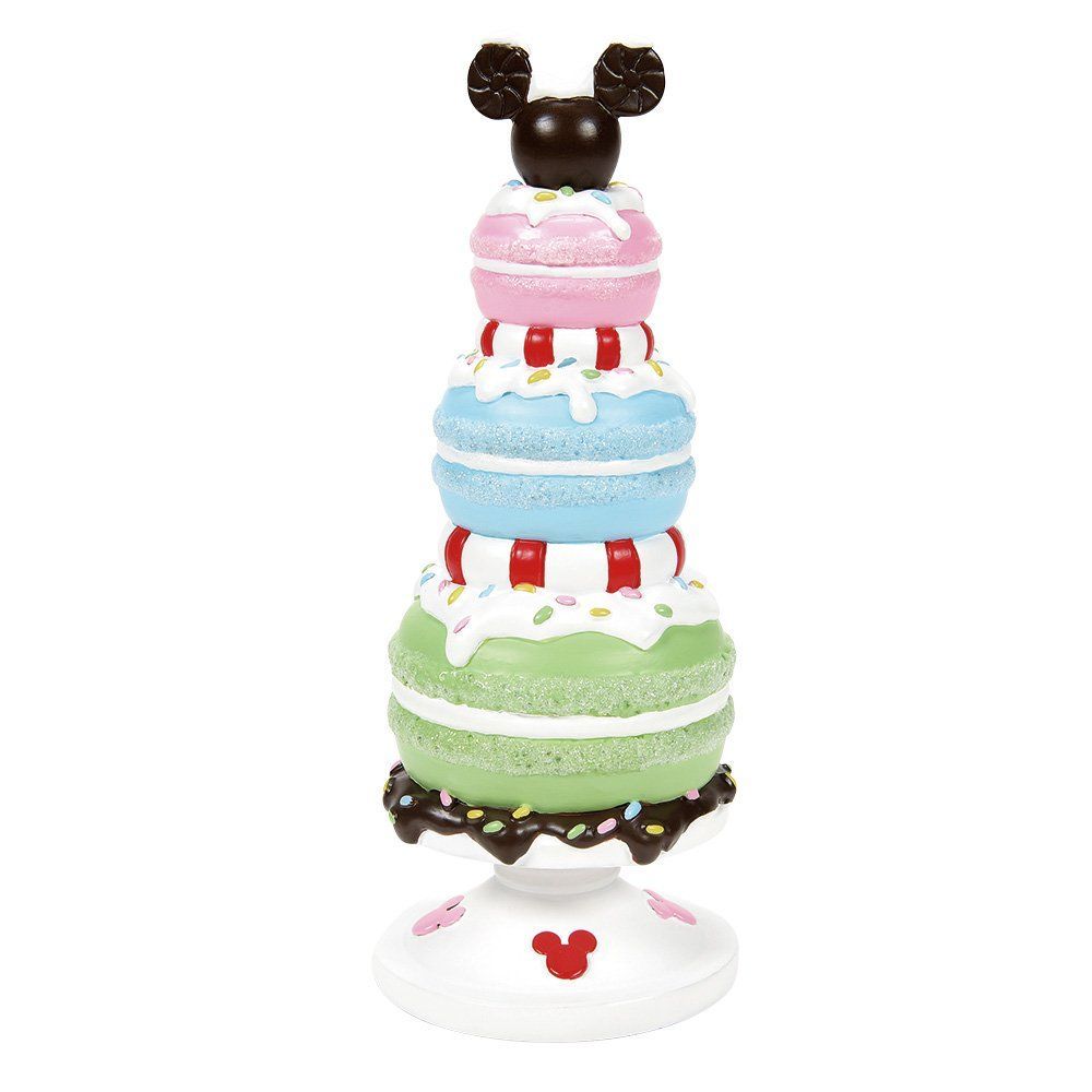 Een macarontoren in de vorm van Mickey Mouse, gevuld met roze, blauwe en groene macarons en bekroond met Mickey's oren, op een witte sokkel.