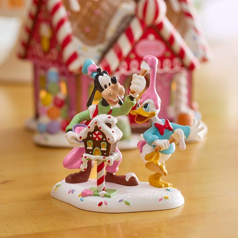Goofy en Donald Duck met een peperkoekhuisje, bedekt met sneeuw en snoep.