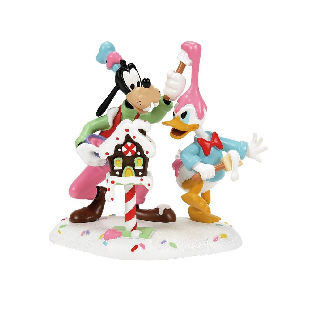 Goofy en Donald Duck met een peperkoekhuisje, bedekt met sneeuw en snoep.