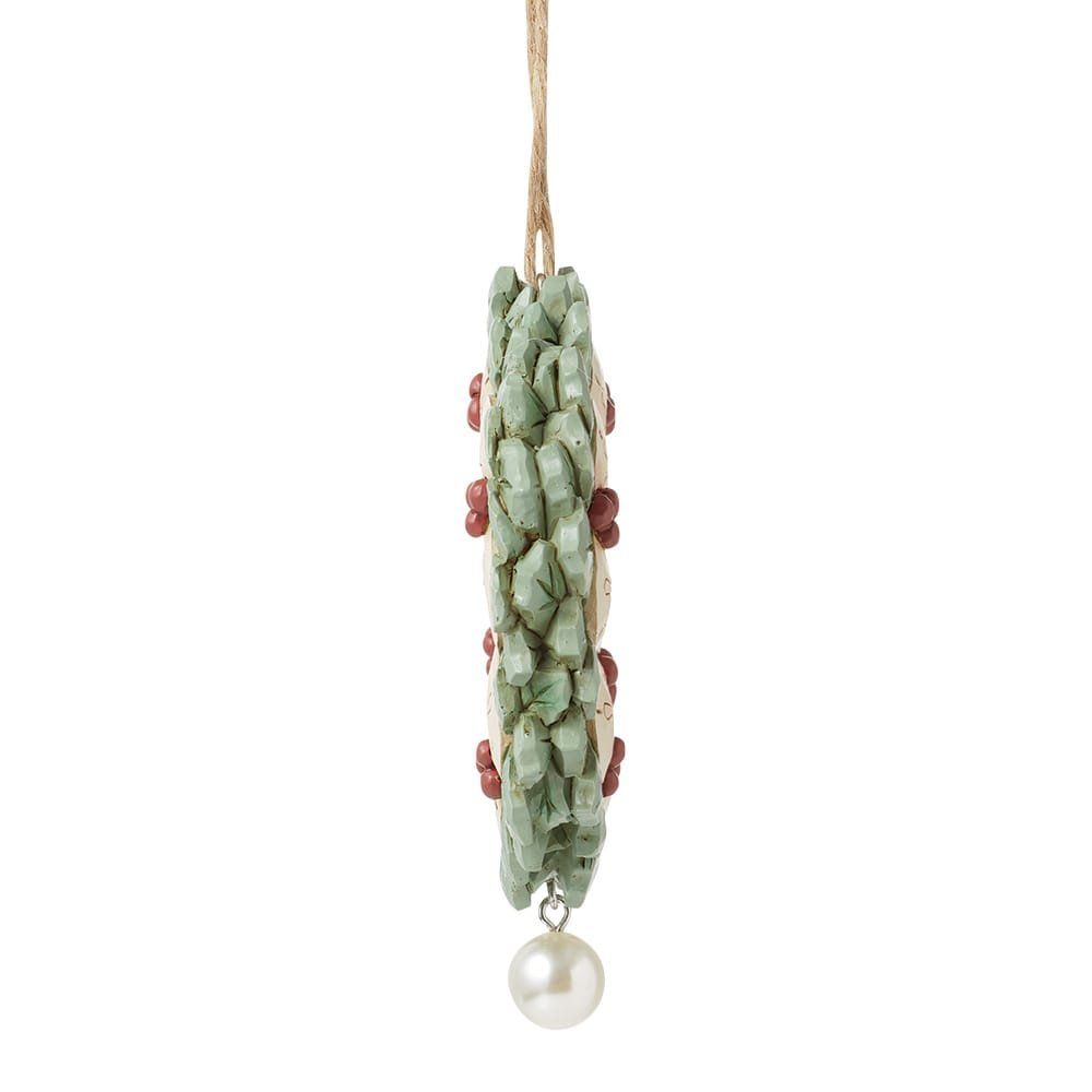 Kerstversiering: groene en beige ring met rode accenten, parel eronder, hangend aan een touwtje.