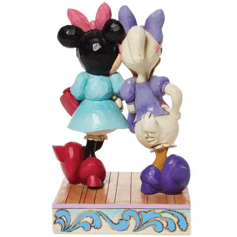 De beeldjes van Minnie Mouse en Daisy Duck omhelzen elkaar op een decoratief platform, beiden gekleed in kleurrijke jurken.