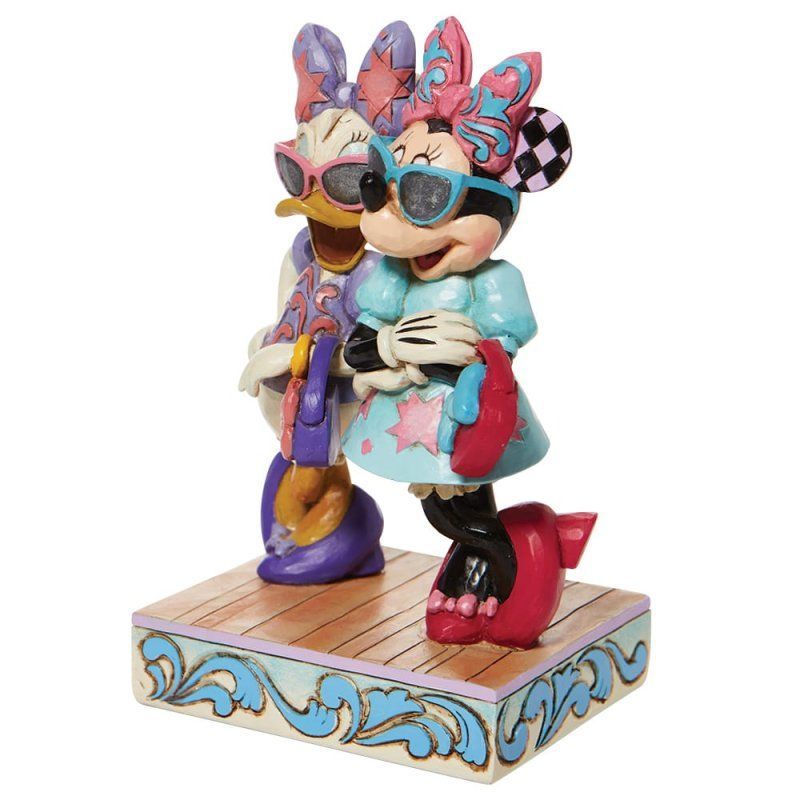 Minnie en Daisy Duck beeldjes met zonnebrillen en pastelkleurige outfits op een decoratieve sokkel.