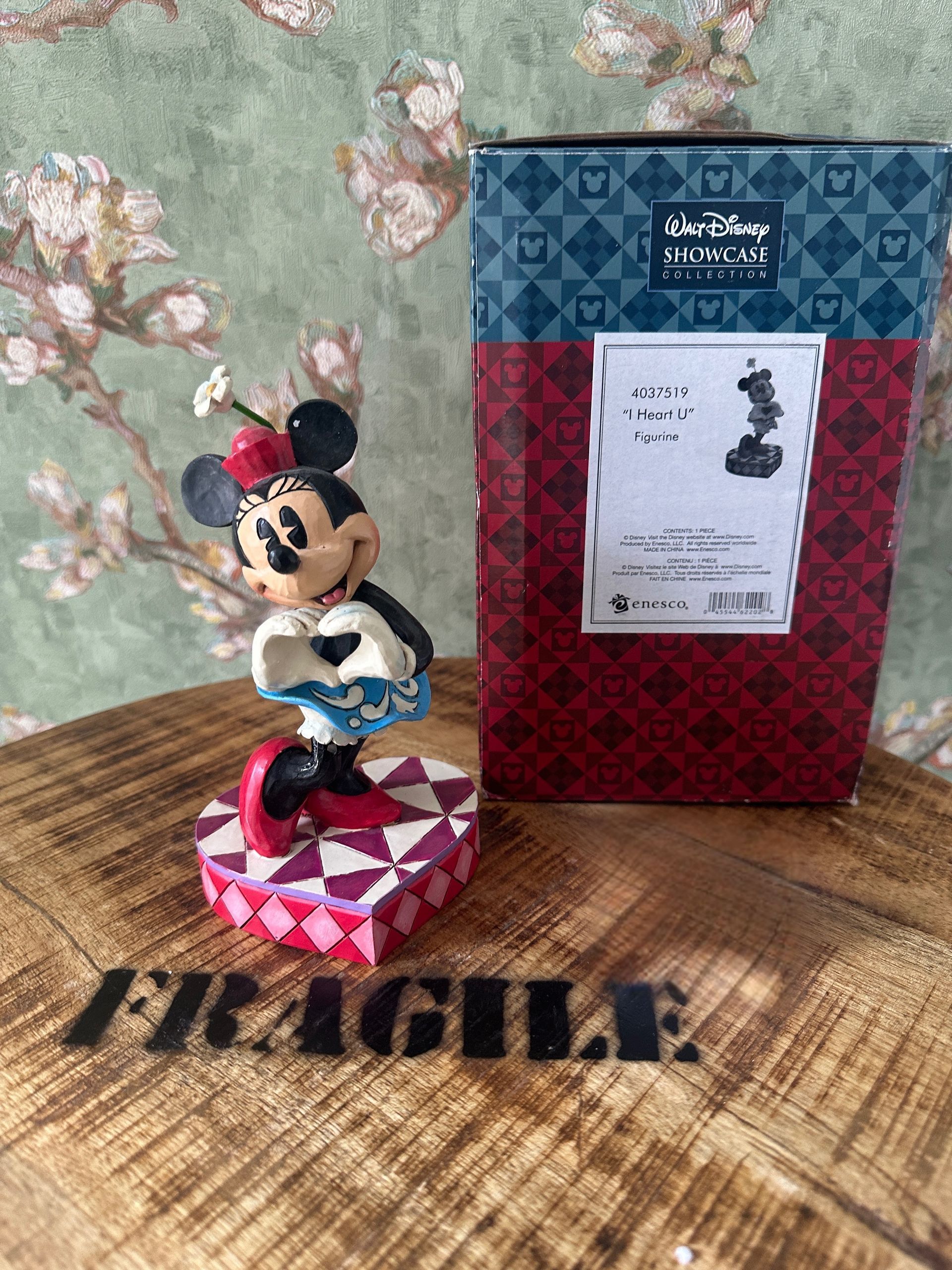 Een Minnie Mouse-beeldje op een geometrische sokkel, naast een Disney Traditions-doos. Op de voorgrond staat het label 