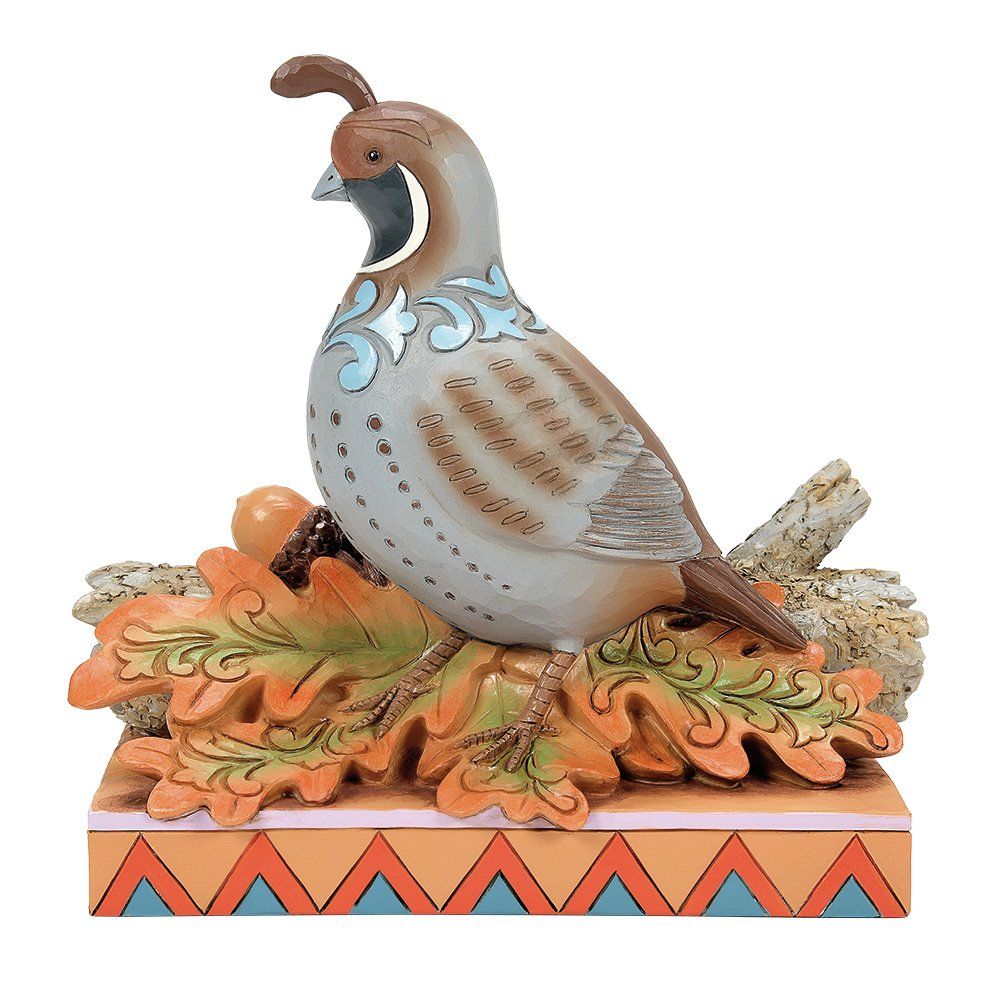 Beeldje van een kwartel met een bruine kuif, rustend op herfstbladeren en een boomstam.