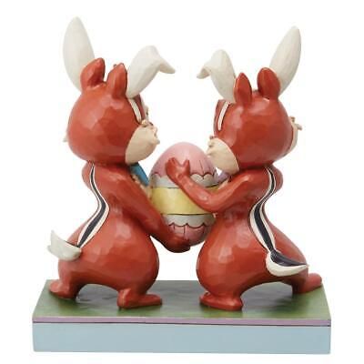 Chip en Dale, verkleed als konijntjes, houden een paasei vast, op een bloemenachtergrond.