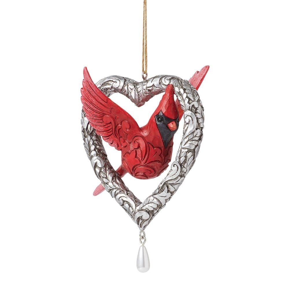 Een rood kardinaalvogelornament in een zilveren hartje met een pareldruppel.