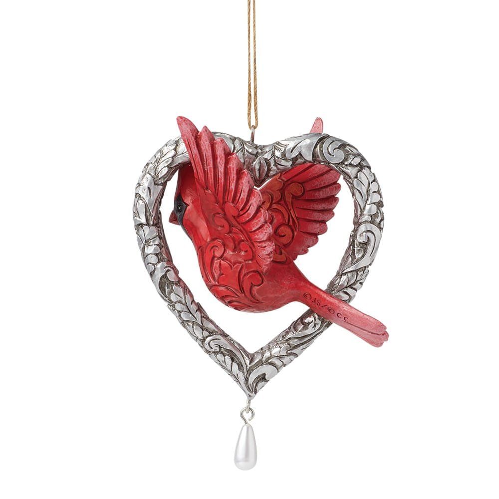 Een rood kardinaalornament in een zilveren hartje met een hangende parel.