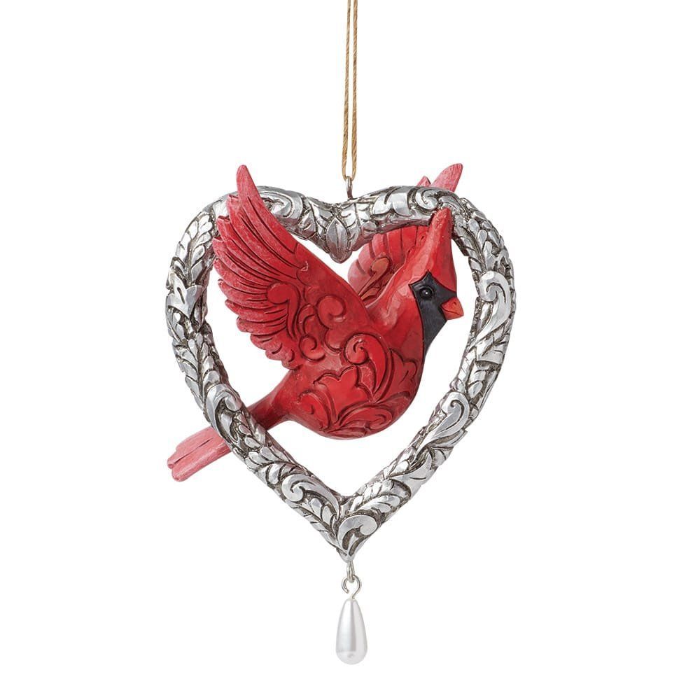Een rood kardinaalvogelornament in een zilveren hartje met een pareldruppel.