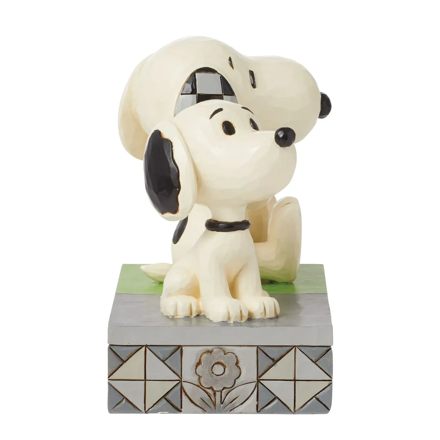 Twee Snoopy-beeldjes, een zittend en een puppy-achtig, op een sokkel met de tekst