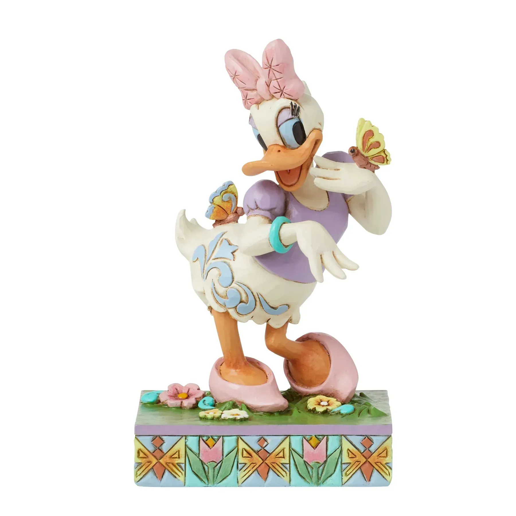 Een beeldje van Daisy Duck met vlinders, met een roze strik in haar haar, lachend, staand op een versierde sokkel.