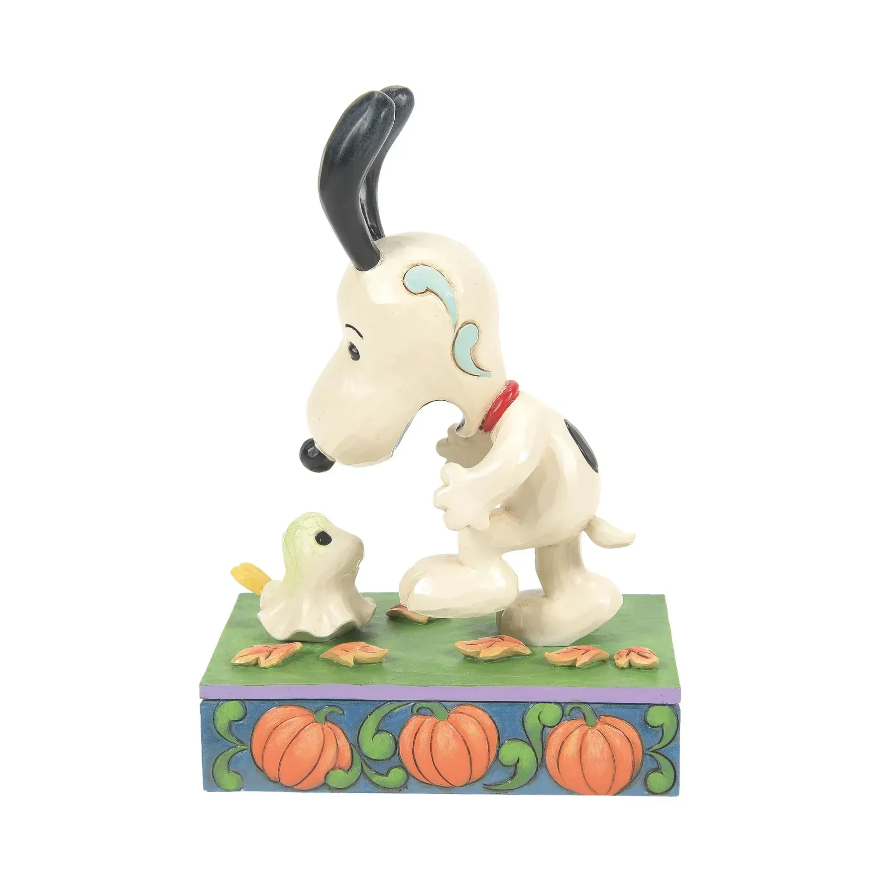 Snoopy en een vogelfiguurtje op een doos versierd met een pompoen. Snoopy kijkt naar de vogel.