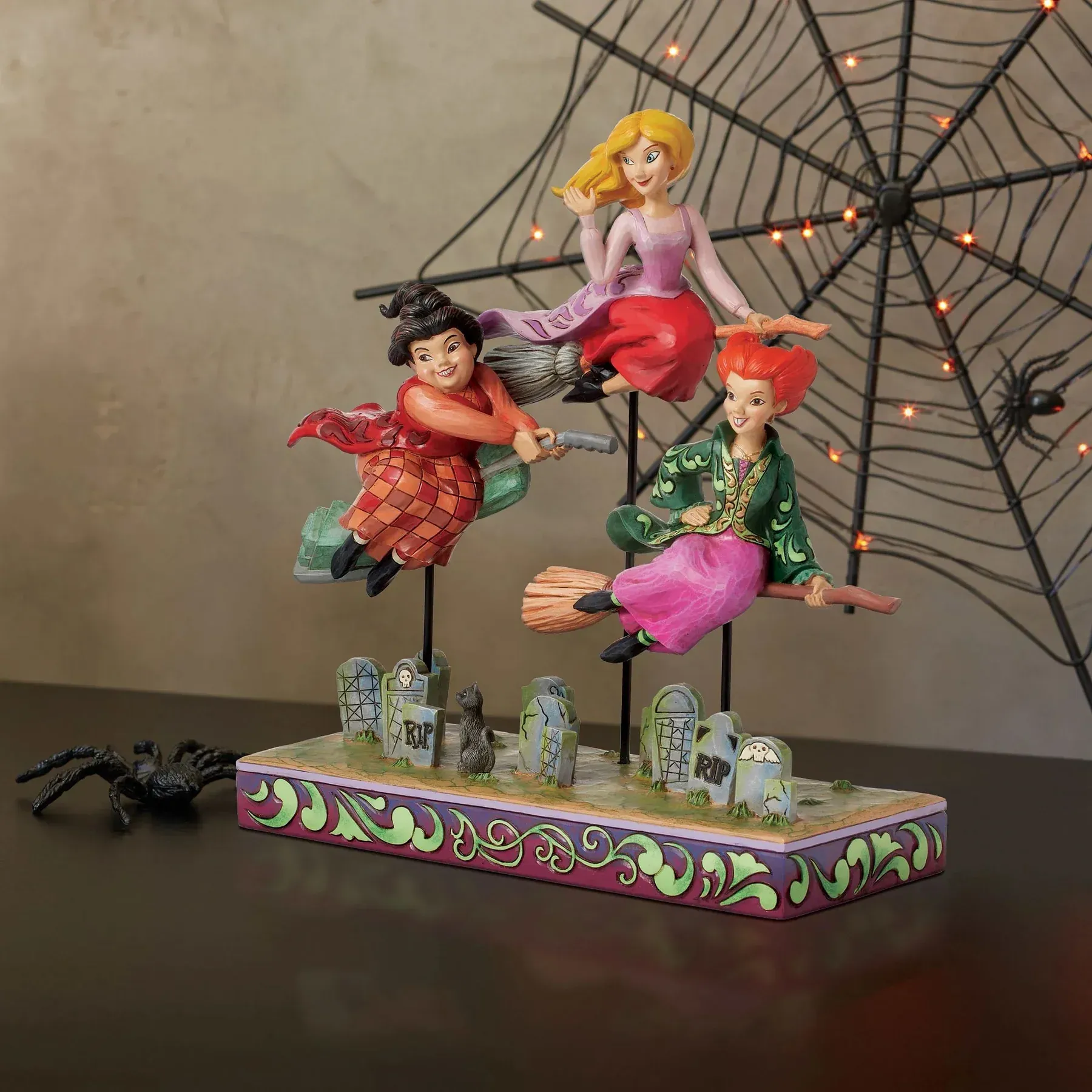 Halloween-figuurtje van drie heksen die op bezemstelen over een kerkhof vliegen.