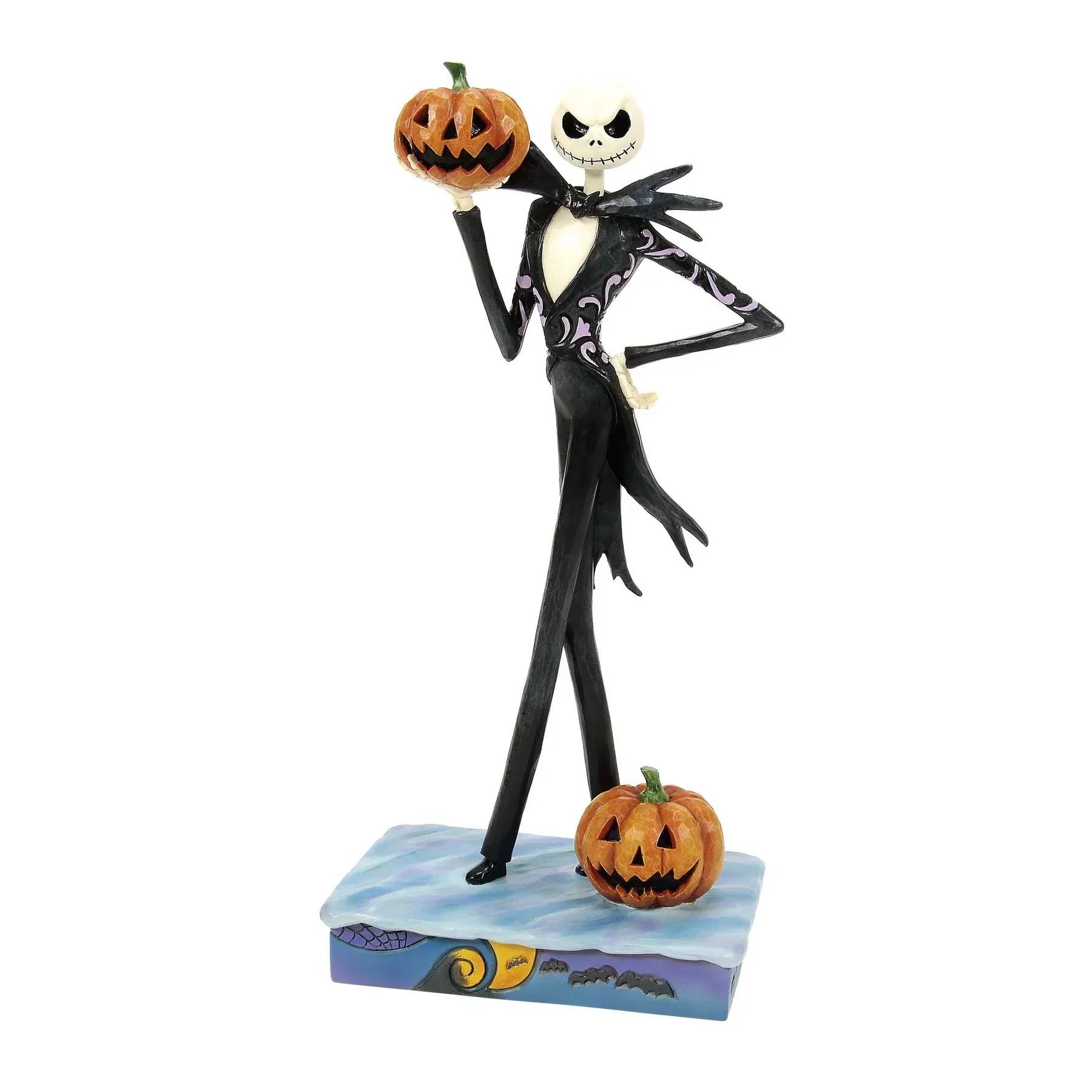 Een beeldje van Jack Skellington die een pompoen vasthoudt, met een pompoen aan zijn voeten, op een sokkel.