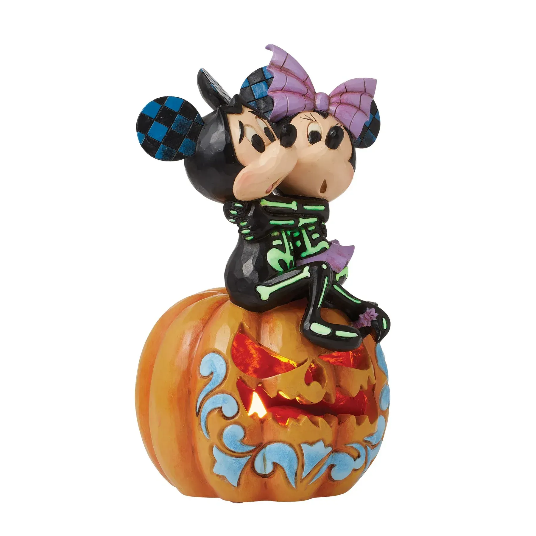 Skeletfiguren van Mickey en Minnie Mouse op een verlichte pompoen, met een Halloween-thema.