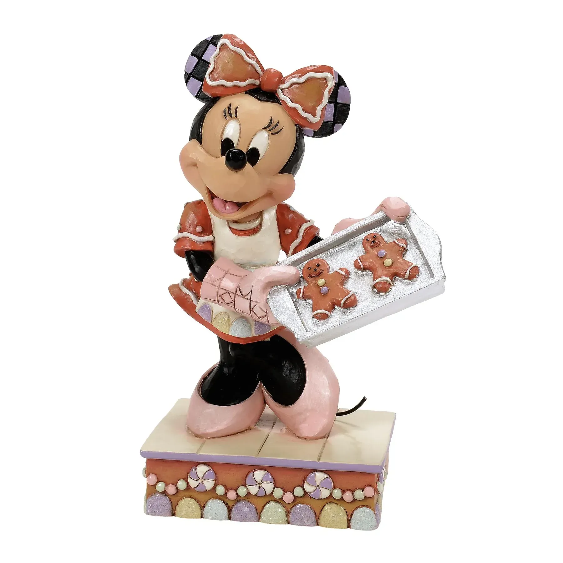 Een Minnie Mouse-figuurtje, gekleed in een peperkoekpakje met schort, met een dienblad vol peperkoekmannetjes in haar handen.