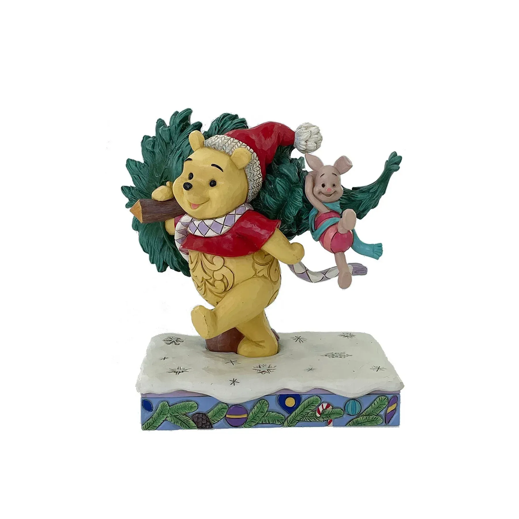 Winnie de Poeh en Knorretje dragen een kerstboom, die op een besneeuwde ondergrond staat. Poeh draagt een kerstmuts en Knorretje houdt zich vast aan een tak.