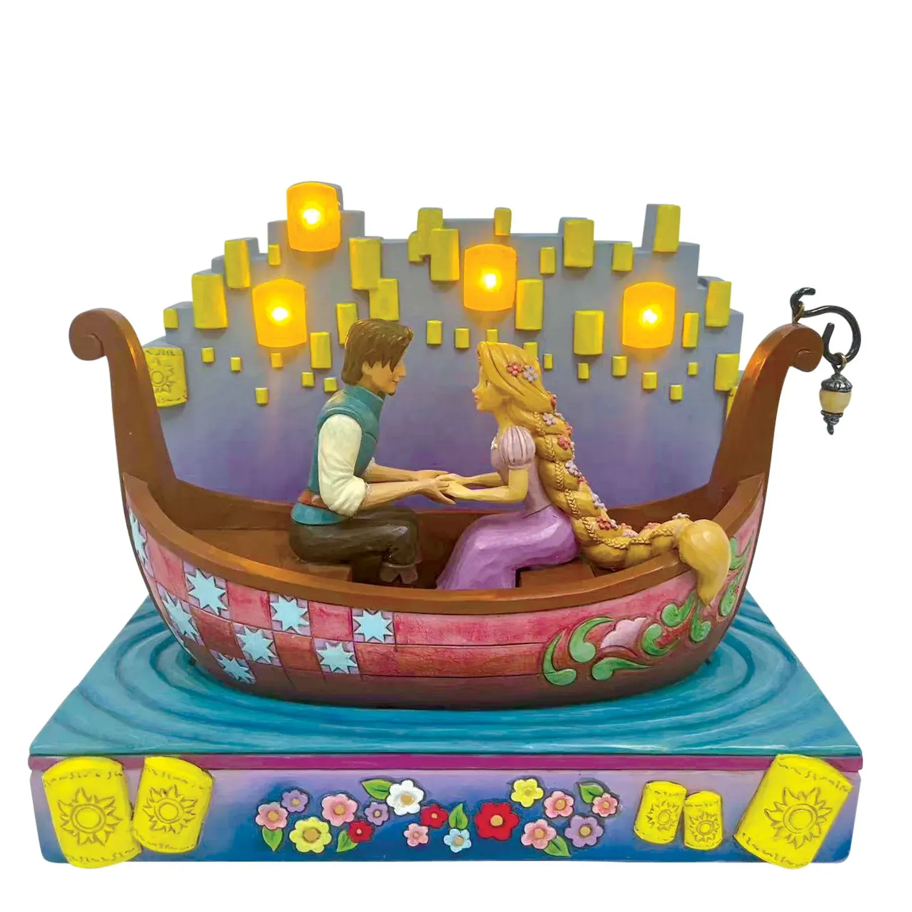 Beeldje van Rapunzel en Flynn in een boot, omringd door drijvende lantaarns, met een blauwe waterbasis en een bloemenversiering.