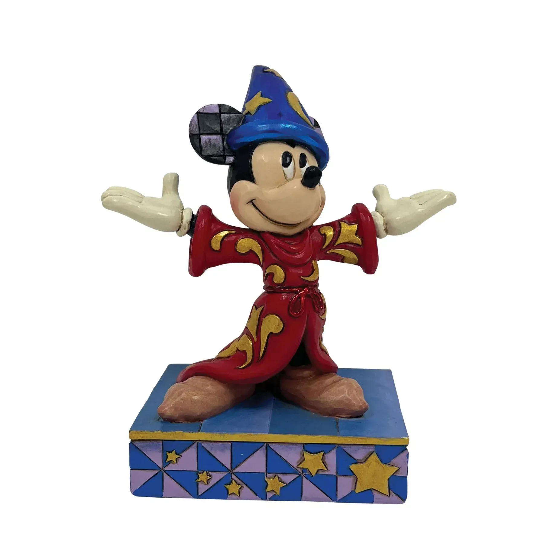 Een Mickey Mouse-figuurtje in tovenaarskleding met uitgestrekte armen, staand op een versierde sokkel.