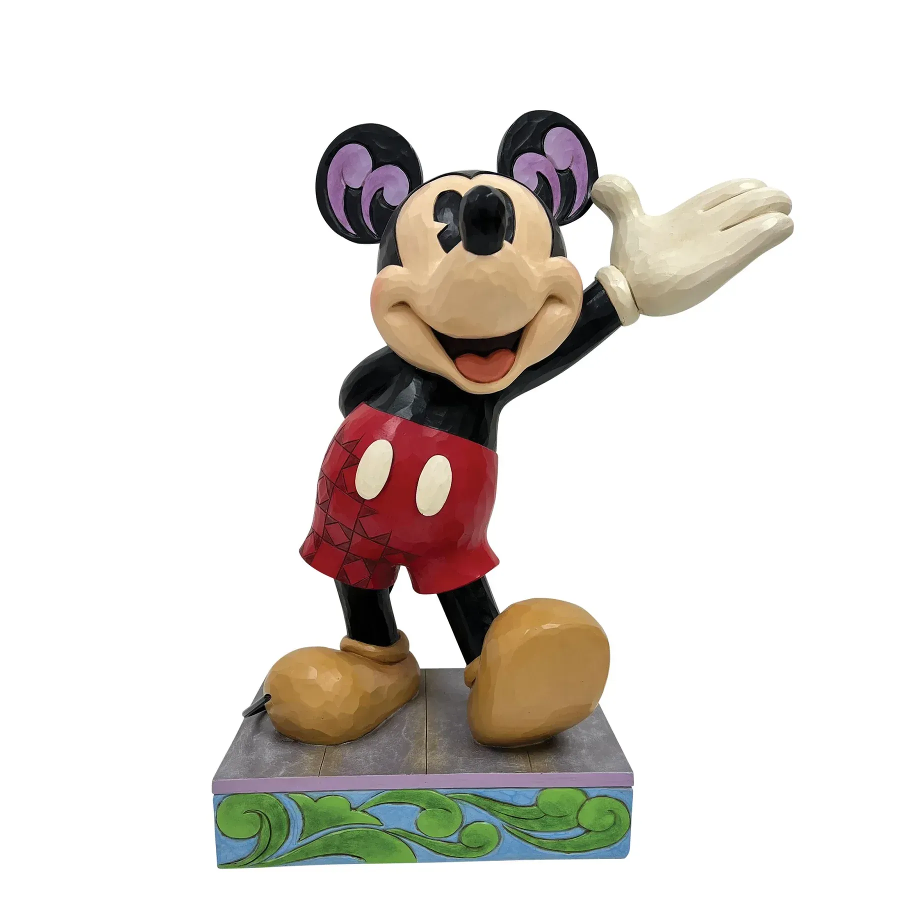 Mickey Mouse-figuurtje, zwaaiend, op een decoratieve sokkel; rode korte broek, zwart lichaam, beige schoenen, paarse oren.
