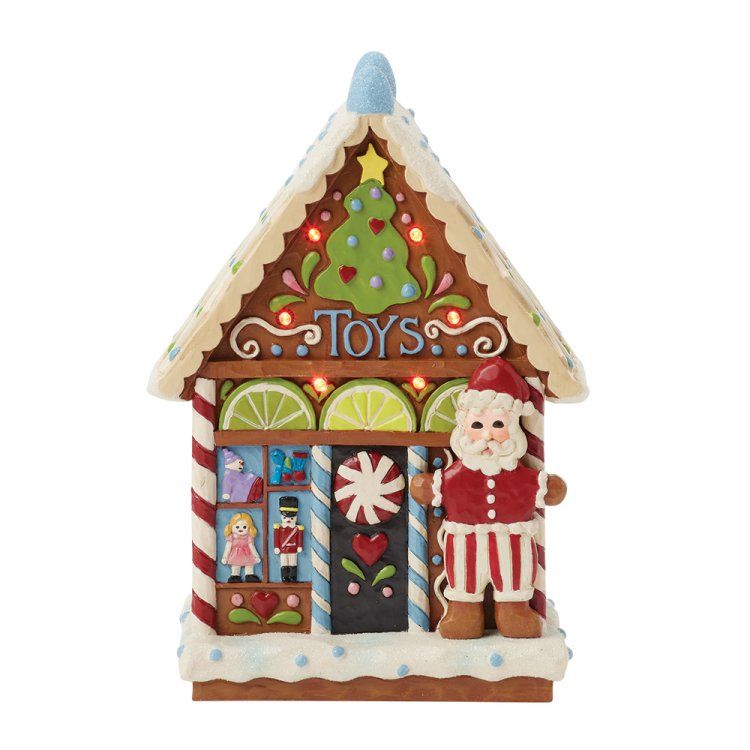 Een speelgoedwinkel van peperkoek met de kerstman, een zuurstok en een verlichte kerstboom.