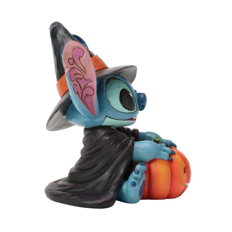 Stitch in heksenkleding met een pompoen in zijn hand. Het blauwe personage draagt ​​een zwarte mantel en een puntmuts.