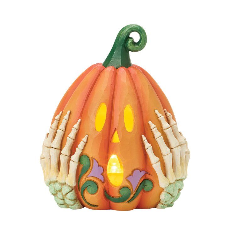 Oranje pompoen als Halloweenversiering met skelettenhanden en een lampje.