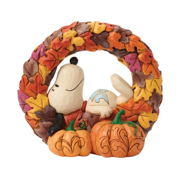 Een Snoopy-figuurtje tussen pompoenen en een krans van herfstbladeren.