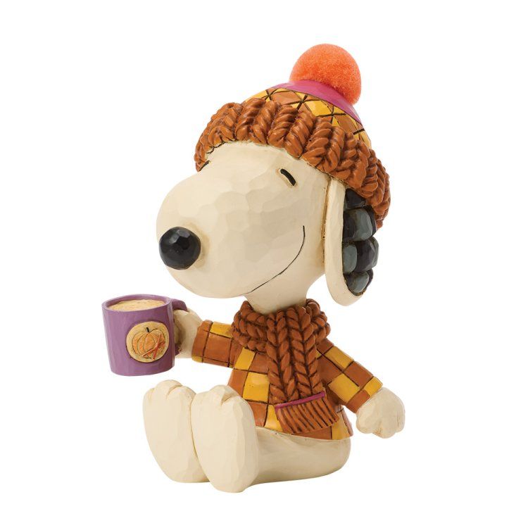 Een Snoopy-figuurtje, met gebreide muts en trui aan, die een paarse mok vasthoudt en lacht.