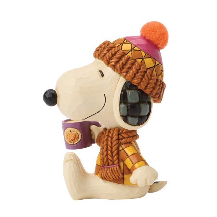 Een Snoopy-figuurtje met een hoed en sjaal, en een mok koffie in zijn hand.