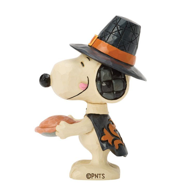 Een Snoopy-figuurtje verkleed als pelgrim, met een taart in zijn hand. Hij draagt ​​een zwarte hoed met oranje rand.