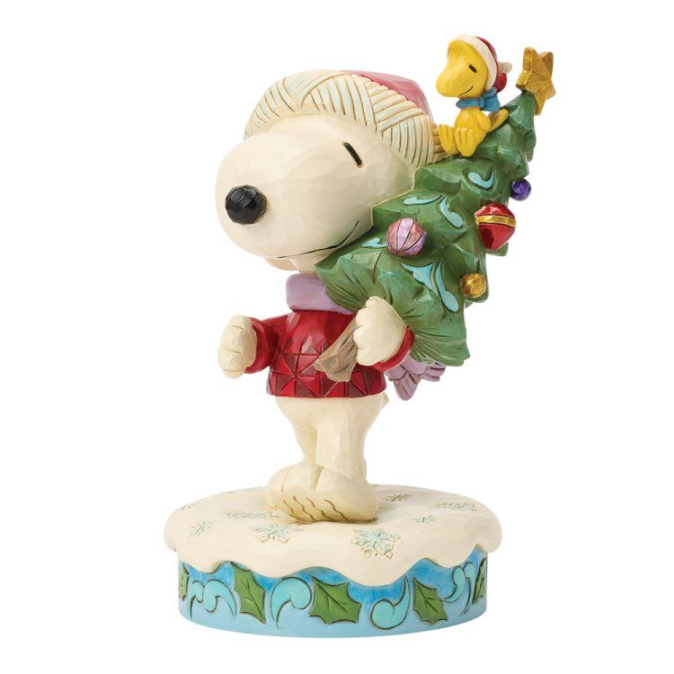 Snoopy in winterkleding, met Woodstock in zijn armen, op een met sneeuw bedekte sokkel.