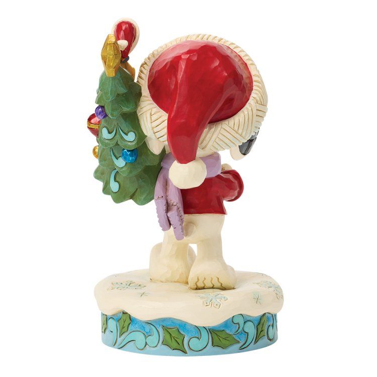 Figuur van een wit dier met een kerstmuts, dat een versierde kerstboom draagt ​​op een besneeuwde ondergrond.