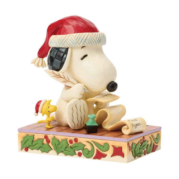 Snoopy met kerstmuts schrijft een brief, Woodstock kijkt toe. Feestelijke sokkel met hulst en een rol tekst 