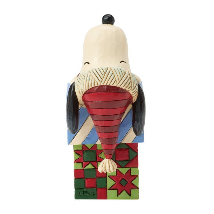 Een standbeeld van Snoopy met een rode hoed, staand op een kleurrijk blok.