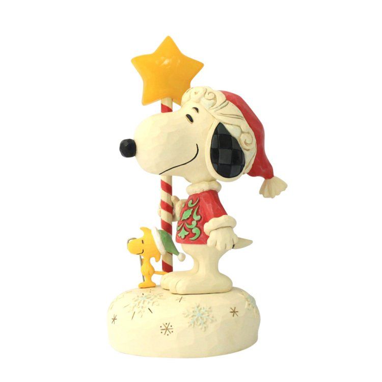 Snoopy met een kerstmuts op en een toverstaf in de vorm van een ster, met Woodstock op een besneeuwde achtergrond.