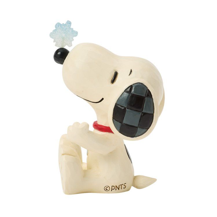 Snoopy-figuurtje met ineengeklemde handen, kijkend naar een sneeuwvlok. Kleuren: lichtbeige, zwart en rood.