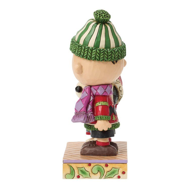 Een figuurtje van Charlie Brown en Snoopy, gekleed in winterkleding, staat op een versierd blok.