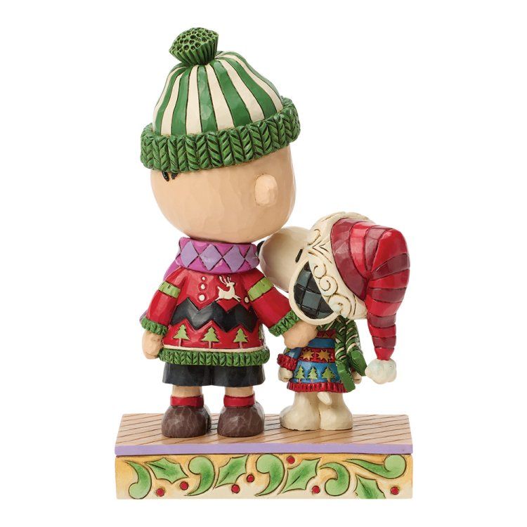 Een beeldje van Charlie Brown en Snoopy, in winterkleding, op een decoratieve sokkel, terwijl ze elkaar omarmen.