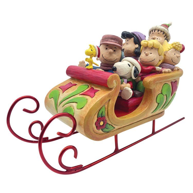Peanuts-figuren in een feestelijke slee, beige en rood met groene details.