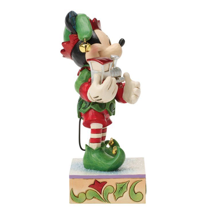 Een elfje van Minnie Mouse in groen en rood met een belletje, dat een klein hoorntje vasthoudt.