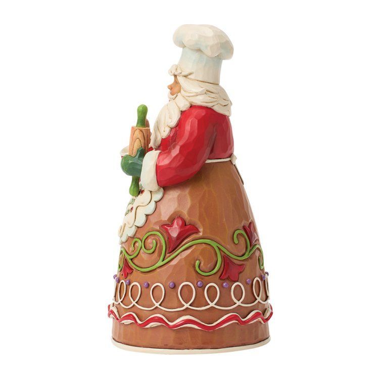 De kerstman, met koksmuts en schort aan, houdt een cupcake en een deegroller vast, versierd in peperkoekstijl.