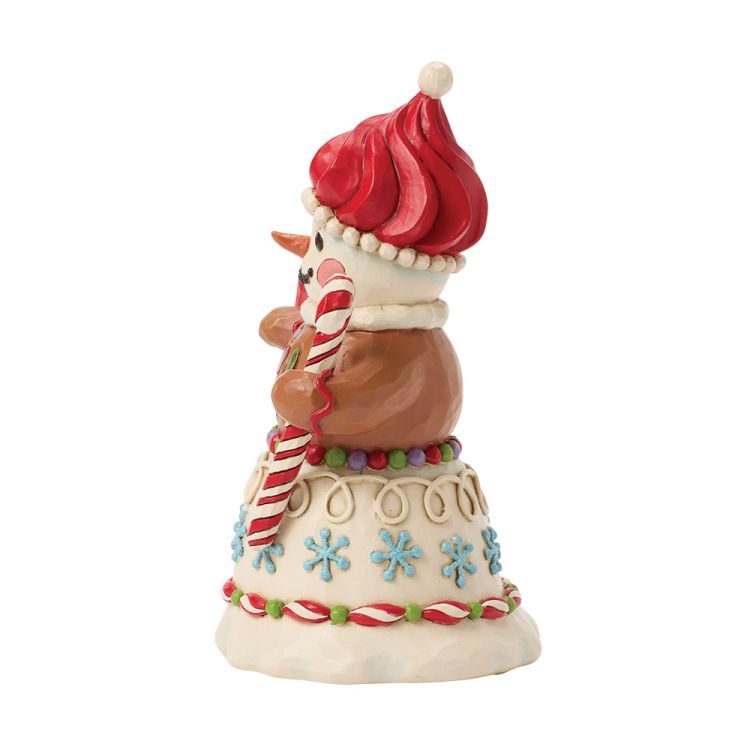 Feestelijke sneeuwpop met een rode muts, een zuurstok in zijn hand en versierd met kerstdecoraties.