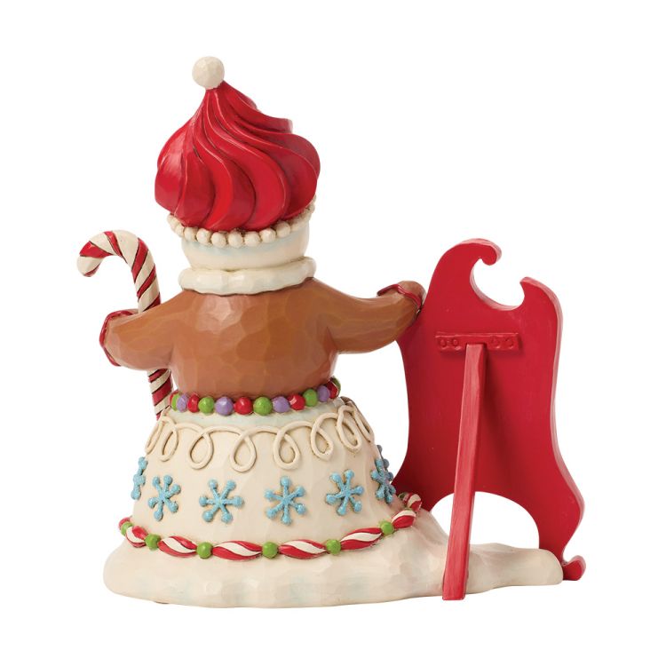 Een peperkoekfiguurtje met een rode hoed en een zuurstok, dat voor een rode schildersezel staat.
