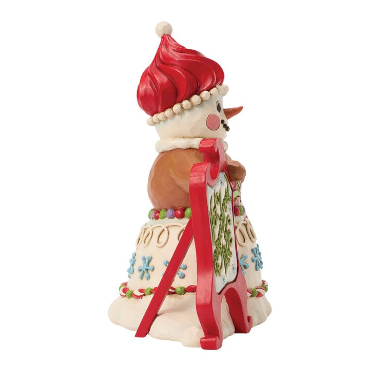 Een beeldje van een peperkoeksneeuwpop met een zuurstok en een bordje met de tekst 
