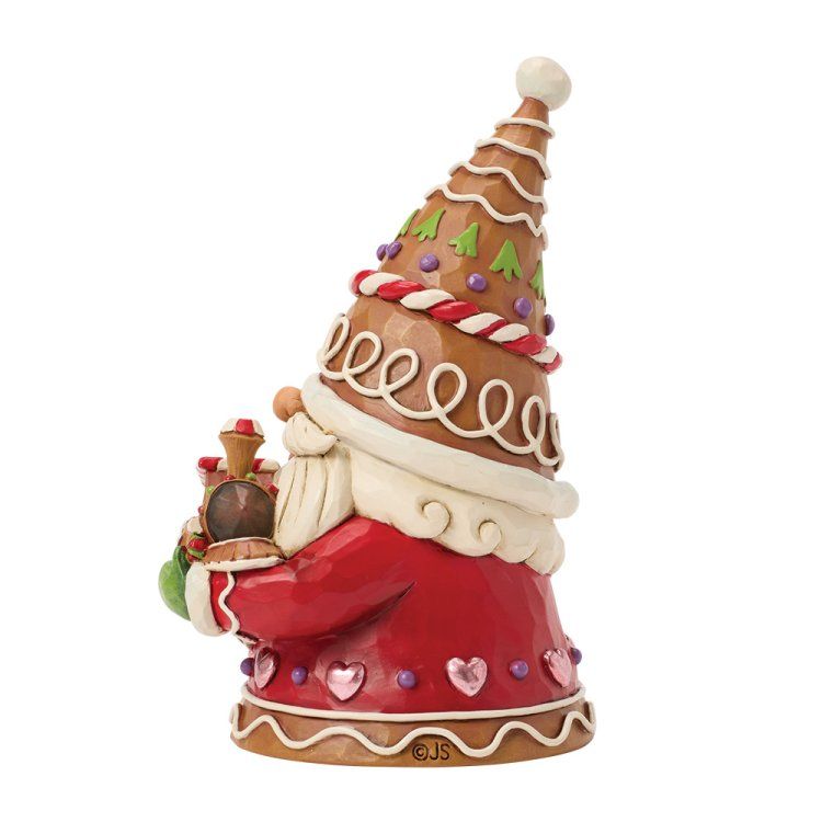 Een kerstfiguur van een peperkoekkabouter die een trein vasthoudt; hij draagt ​​een hoge, versierde hoed en een rood pak.