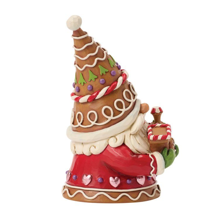 Een peperkoekfiguurtje van de kerstman met een klein cadeautje in zijn hand. Hij draagt ​​een rode jas en een versierde muts.