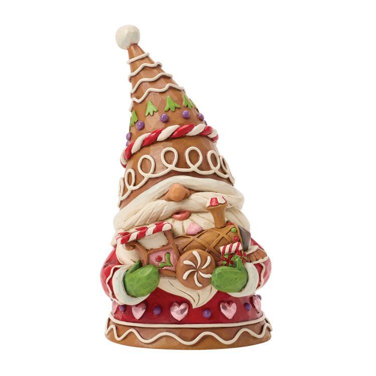 Een kerstfiguur van een peperkoekkabouter die een trein vasthoudt; hij draagt ​​een hoge, versierde hoed en een rood pak.