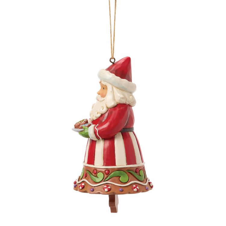 Een kerstmanfiguur met een rood-wit gestreepte jas, die een bord met koekjes vasthoudt.