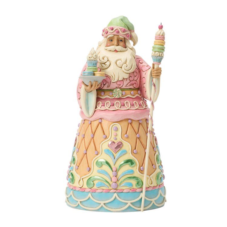 Een pastelkleurig kerstmanfiguurtje met een kaars en een staf met een gekrulde bovenkant, gekleed in een roze gewaad en een groene muts.