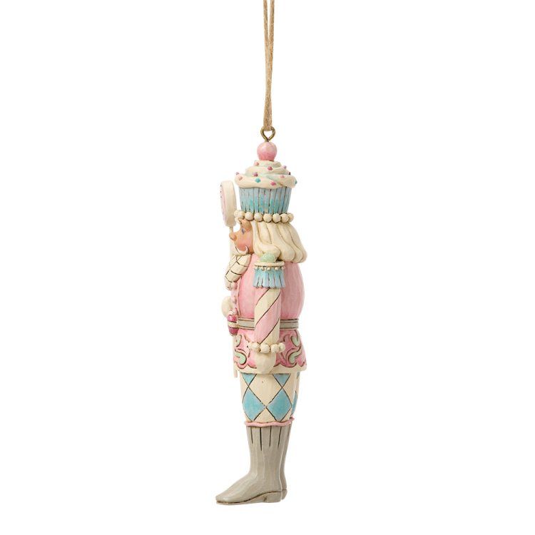 Een roze en blauwe notenkraker-ornament met een lolly in zijn hand en een cupcake-hoedje op.